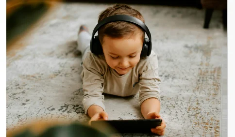 young boy on floor watching an i pad with headphones on