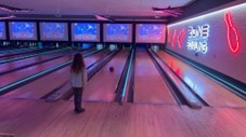 a child watches a bowling ball roll down a ten pin bowling alley